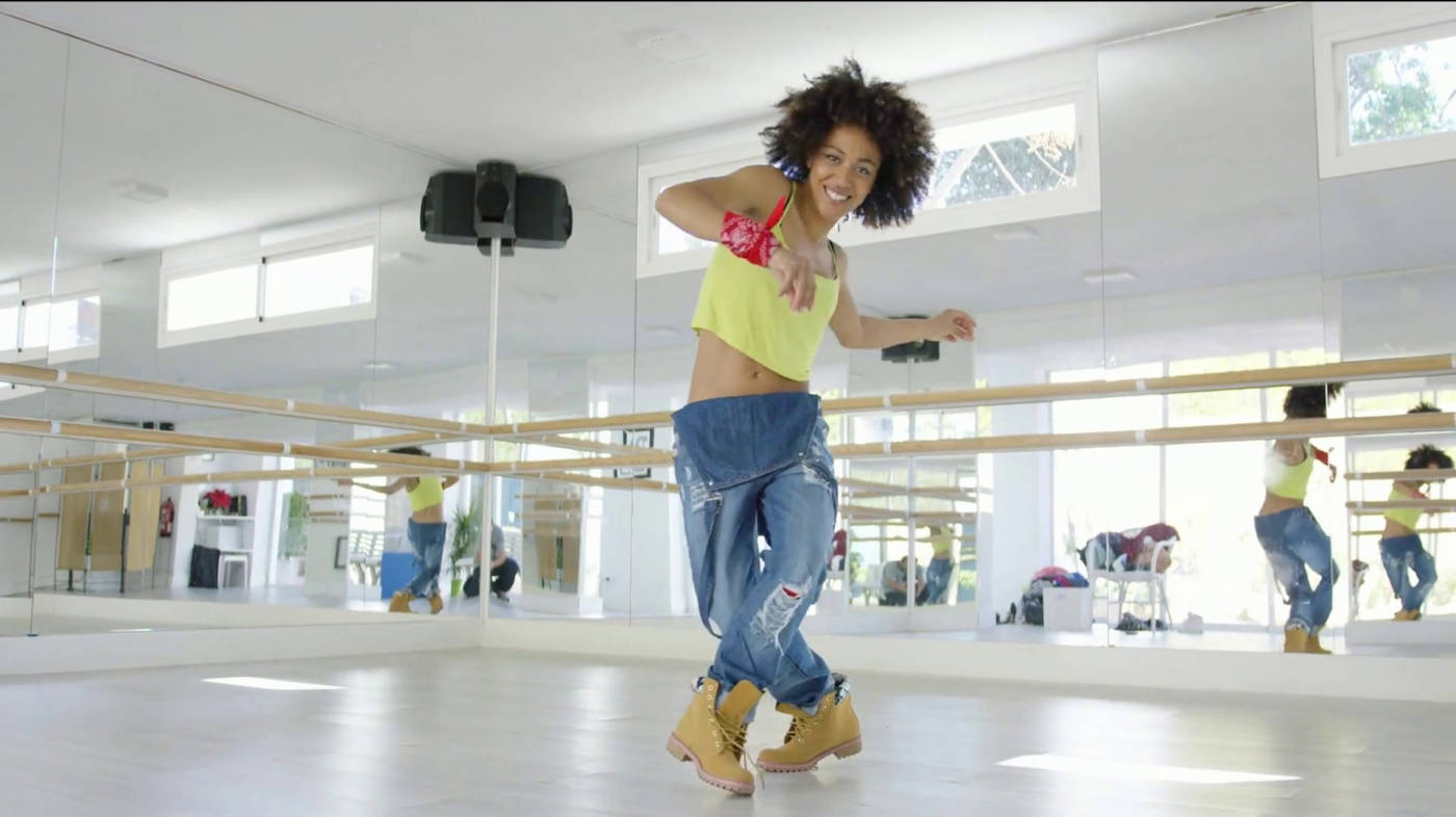 A smiling African American woman dancing in the dance studio and having fun