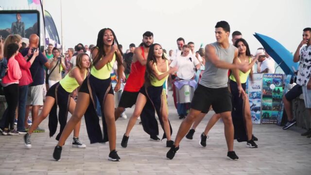 Men and women smiling and dancing zumba on the street