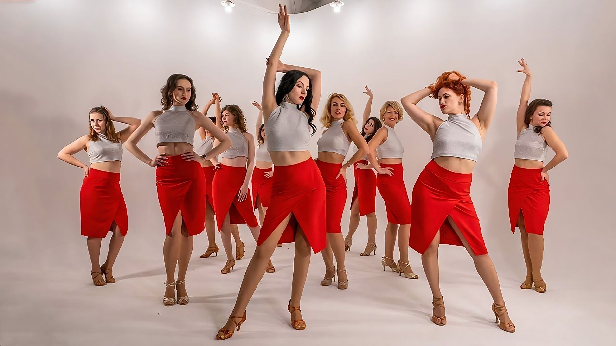 Women in red skirts and while tops posing beautifully on a white stage