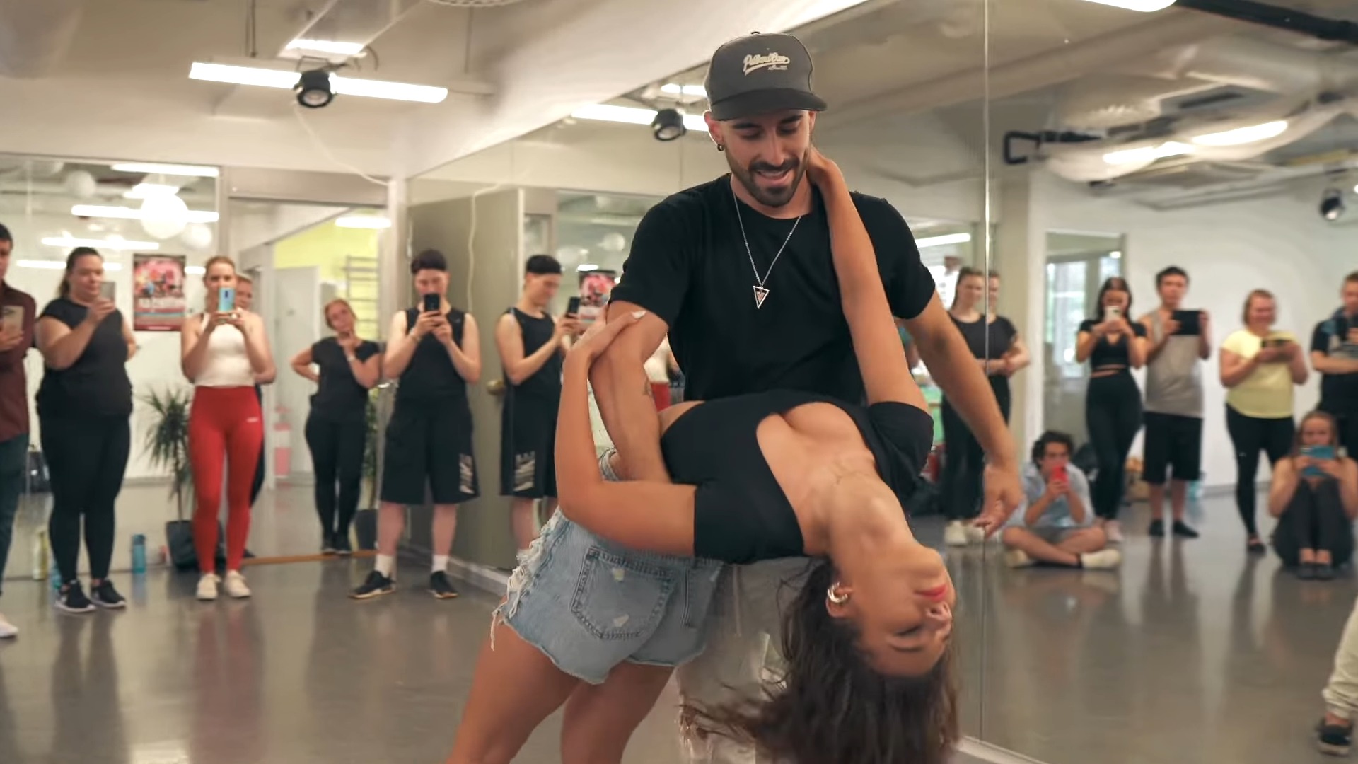 Man and woman dancing bachata in front of their dance students in the studio