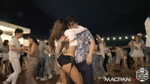 Man and woman dancing bachata among other dancers on a social dance night event