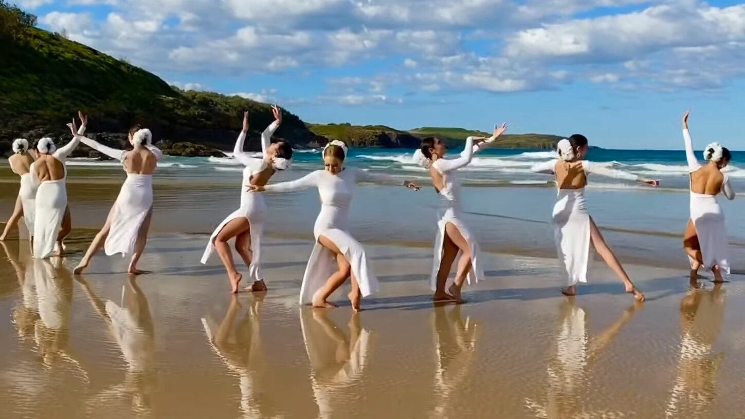 Women in white dresses dancing on the beach