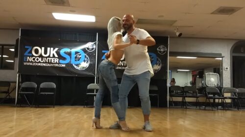 Blond woman and bald man in blue jeans dance kizomba and zouk in the studio