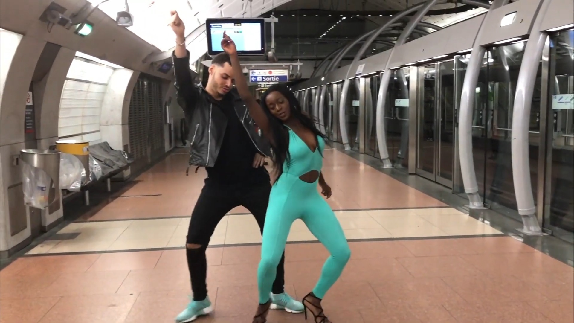 White man and black woman dancing in public in a subway station