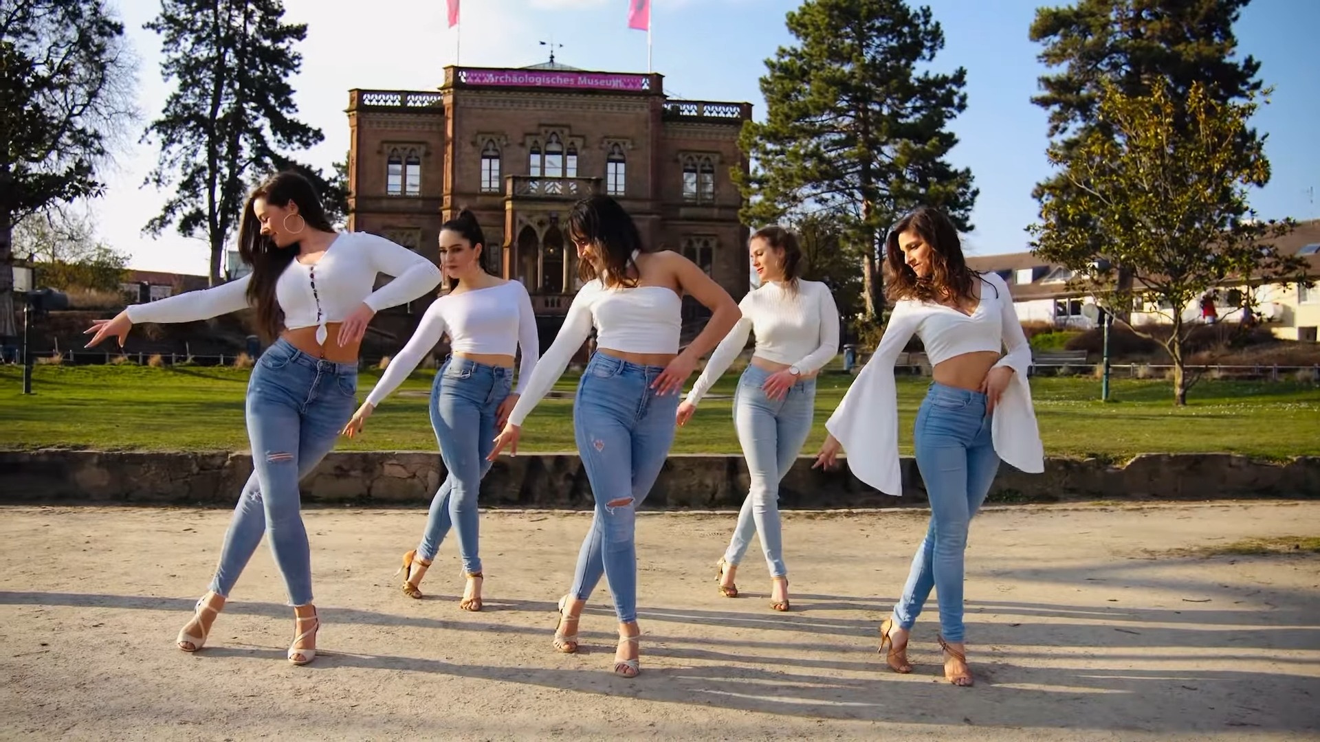 Five women in blue jeans and white top dancing Kizoba in front of a German castle