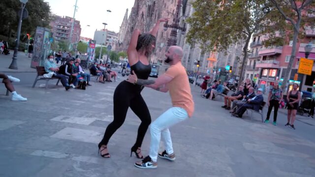 Man and woman dancing in front of Sagrada Familia in Barcelona and passers by