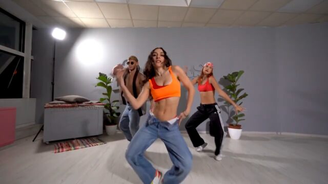 Two women and one man dancing reggaeton in dance studio